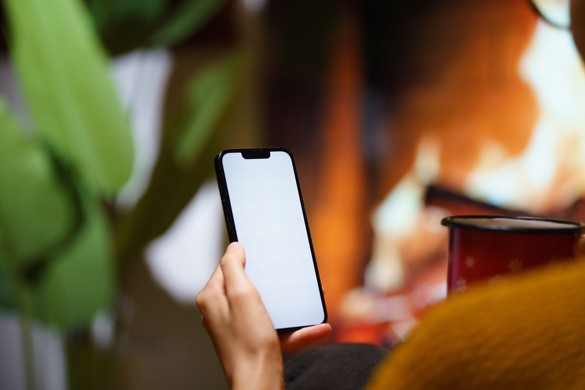 Osoba obsługująca smartfon przy kominku w przytulnym salonie