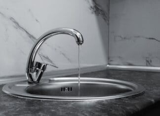 Chromowany kran z płynącą wodą w nowoczesnej kuchni